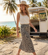 Woman wearing a black and cream wavy stripe satin bias cut skirt with a midi length and elastic waist.