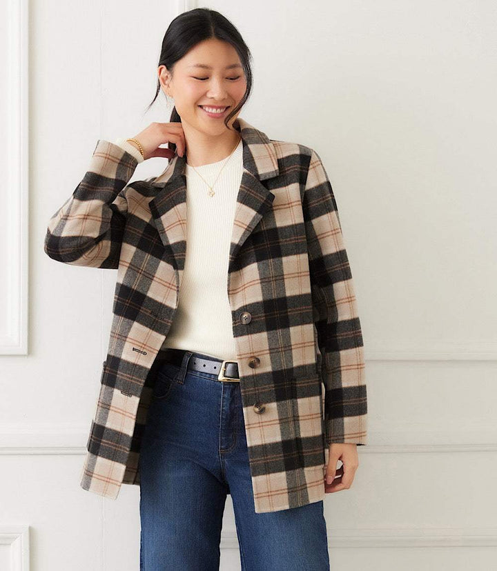 Woman wearing oversized plaid blazer with beige, black, and brown pattern over white top and jeans