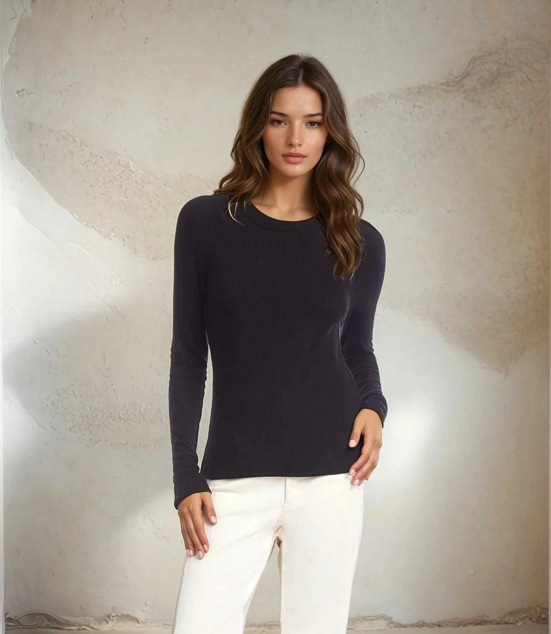 Woman wearing a fitted long sleeve ribbed crewneck top in dark color paired with white pants