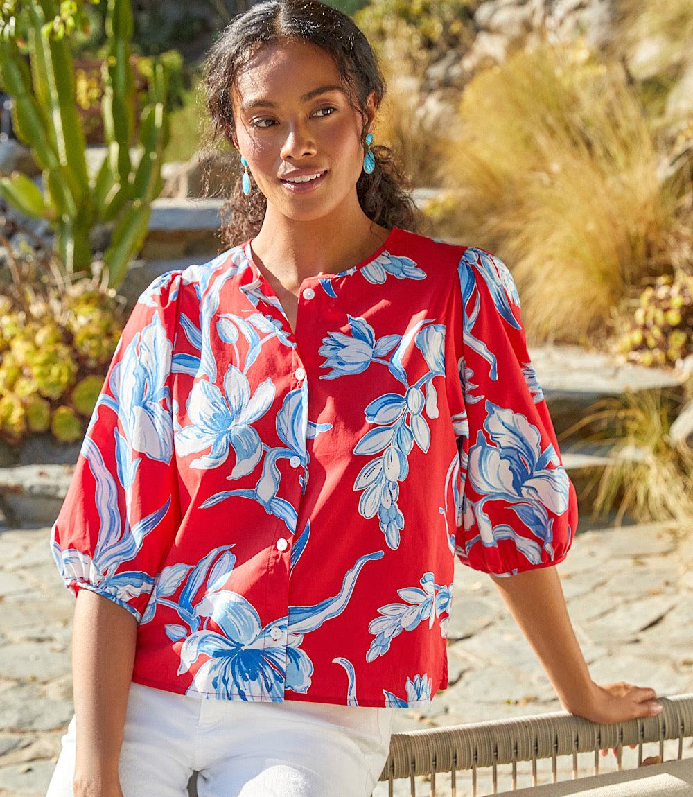 Woman wearing red puff sleeve button-front shirt with blue and white floral print outdoors