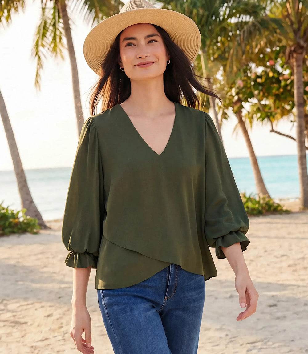 Woman wearing a silky crepe layered sleeve asymmetric top with V-neck and gathered shoulders