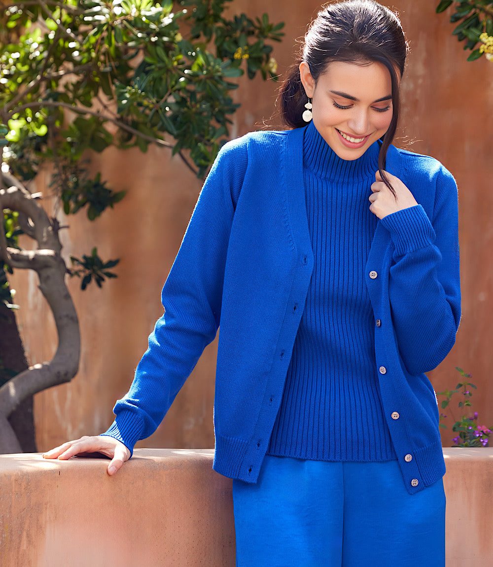 blue V-neck cardigan sweater with front button closure and ribbed cuffs worn by woman outdoors