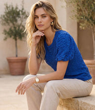 Woman wearing a puff sleeve textured top with short puff sleeves and crew neckline