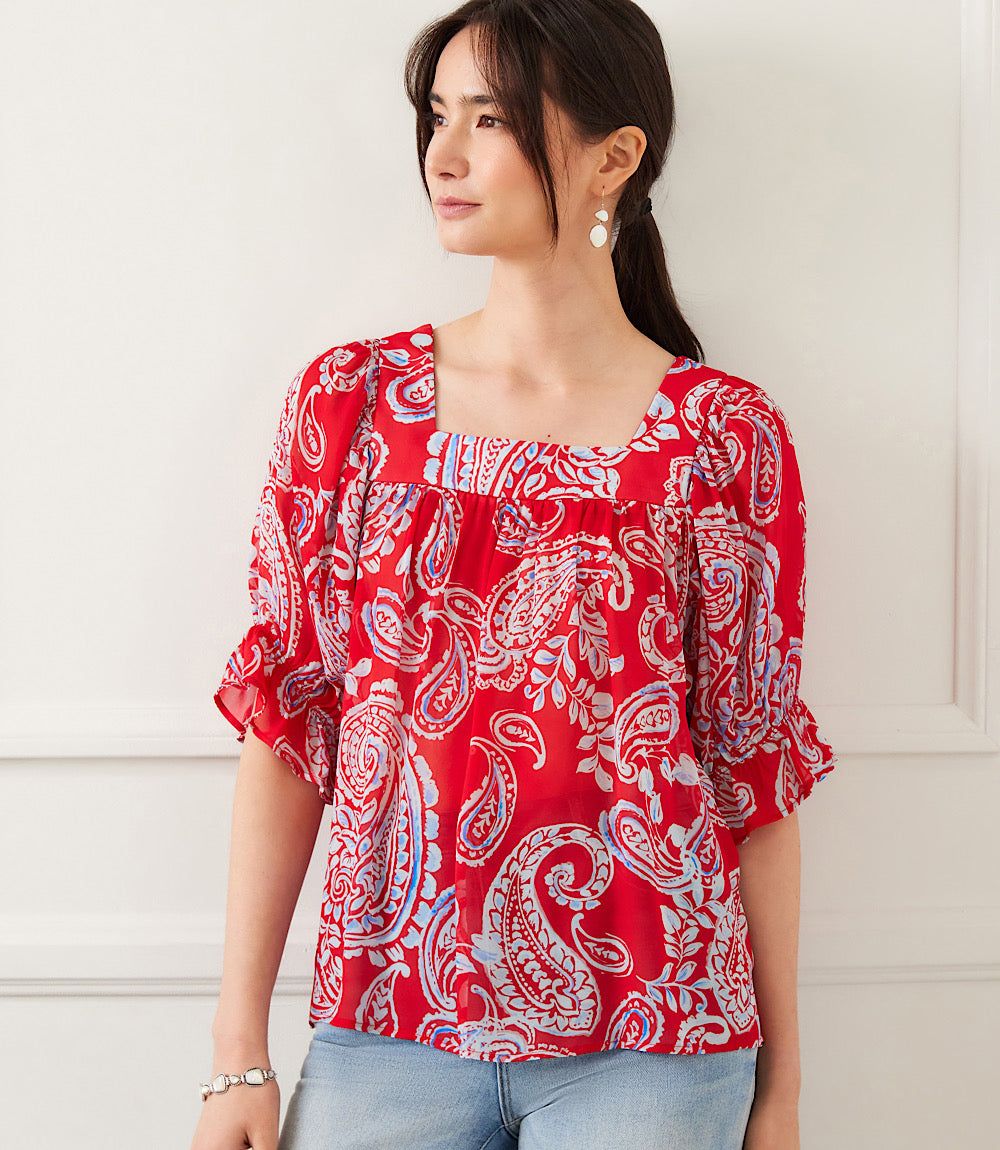 Woman wearing red ruffle sleeve top with light blue and white paisley print and square neckline