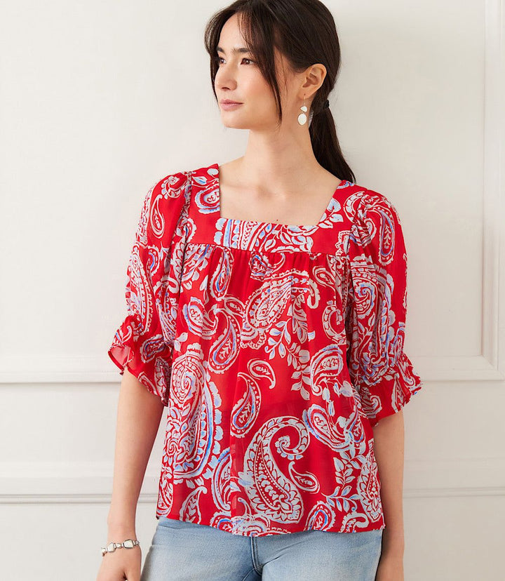 Woman wearing red ruffle sleeve top with light blue and white paisley print and square neckline