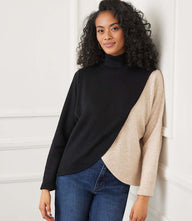 Woman wearing a long sleeve crossover colorblock top with a mock neck and curved hemline
