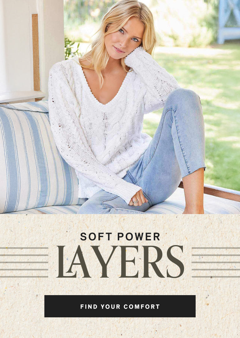 Woman wearing a white sweater and blue jeans sitting on a striped cushion with text 'Soft Power Layers' and 'Find Your Comfort'.