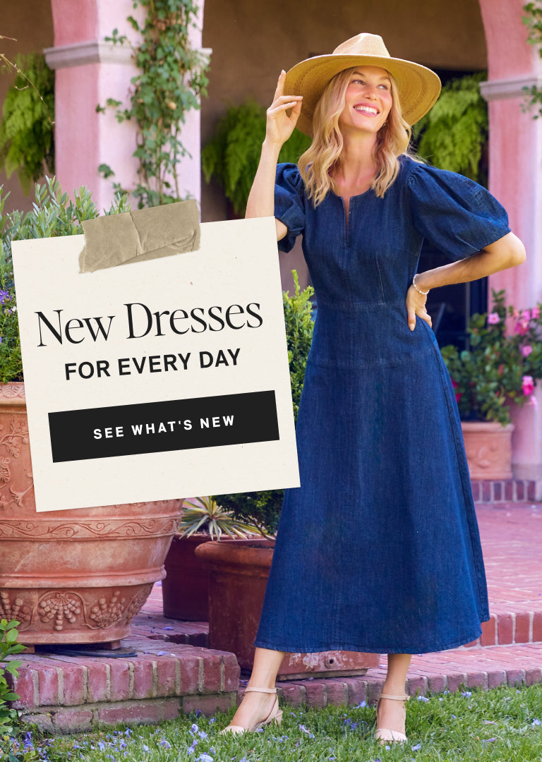 Woman in a blue dress and hat holding a sign about new dresses, standing outdoors.