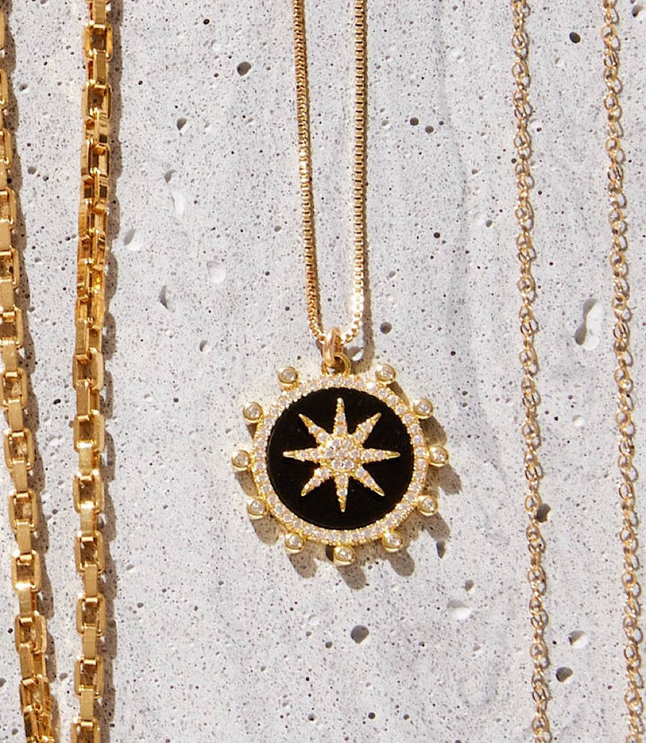 Gold Starburst Charm Necklace with black enamel and micro pave cubic zirconia pendant on a delicate chain