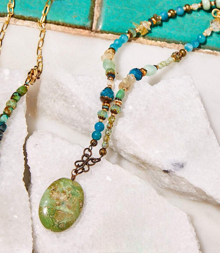 Gemstone beaded pendant necklace with earth-toned and aqua stones, adjustable length and lobster clasp closure.