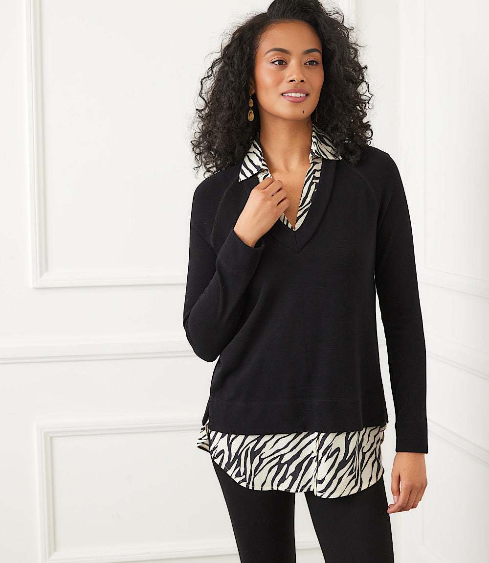 Woman wearing a layered contrast zebra sweater with zebra print collar and hem, black long sleeves, and relaxed fit.