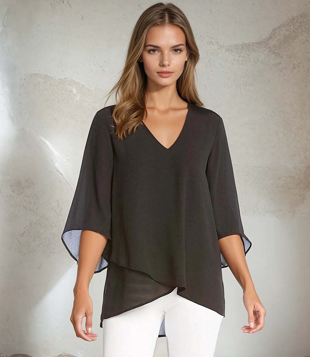 Woman wearing black silky crepe Bracelet Sleeve Asymmetric Top with V-neck, flare sleeves, and layered asymmetrical hem.