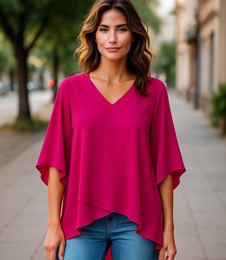 Woman wearing a fuchsia Bracelet Sleeve Asymmetric Top with V-neck and layered, flowy hem paired with blue jeans outdoors