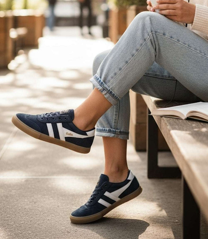 Gola Badminton Suede Plimsoll navy sneakers with white wingflash logo and gum rubber sole worn with jeans