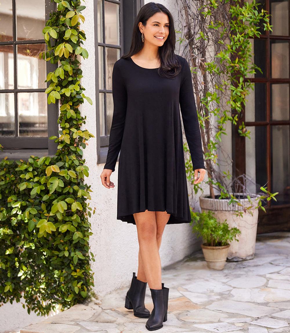Woman wearing black Long Sleeve Maggie Trapeze Dress with scoop neck and high-low hem standing outdoors