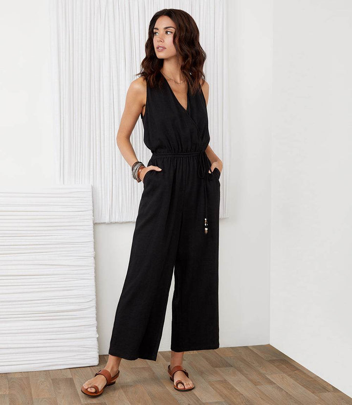Black cropped jumpsuit with sleeveless surplice neckline and wide-leg silhouette made from linen blend with beaded self-belt and side pockets.