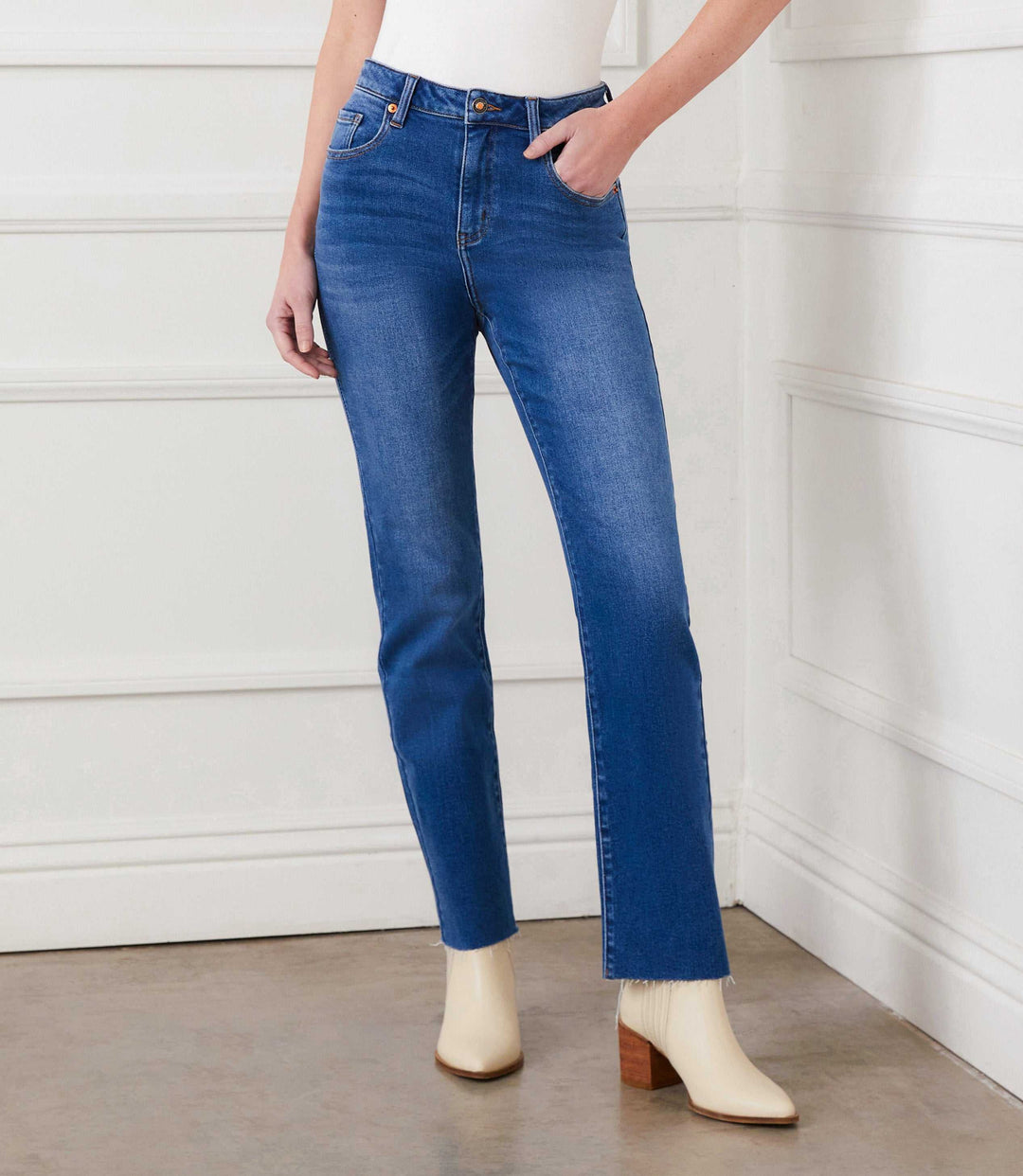 Blue raw hem straight jeans with high rise and five pockets worn with white boots