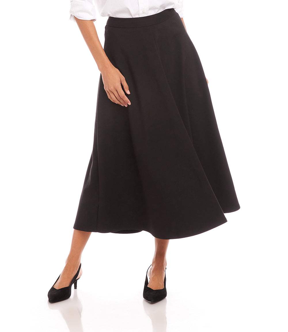 Woman wearing black midi circle skirt with side zipper and elastic waistband, paired with white blouse and black heels.