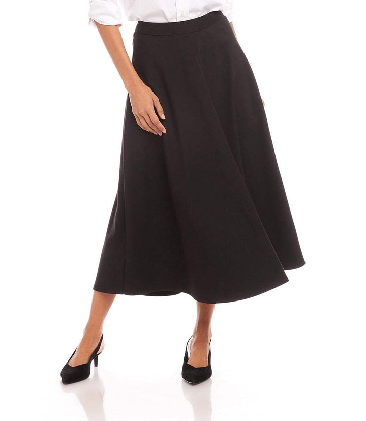 Woman wearing black midi circle skirt with side zipper and elastic waistband, paired with white blouse and black heels.