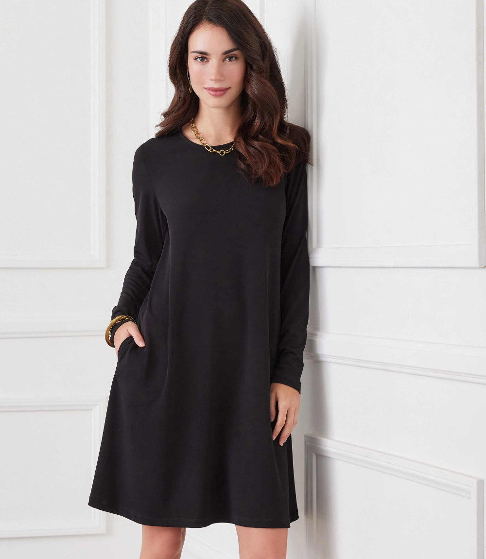 Woman wearing a black long sleeve travel jersey dress with side pockets and crew neckline