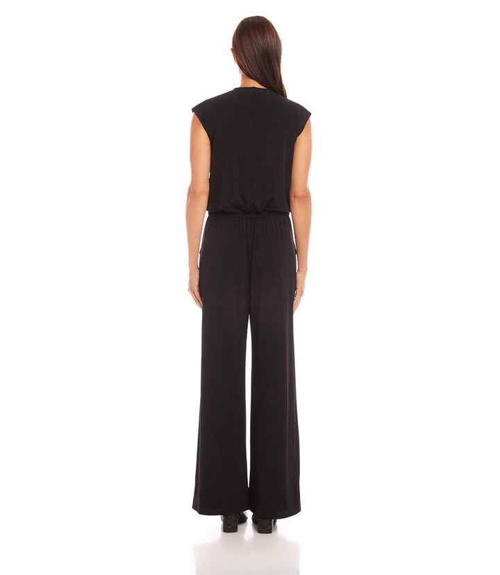 Back view of a woman wearing a black sleeveless travel jersey jumpsuit with wide legs and elastic waistband