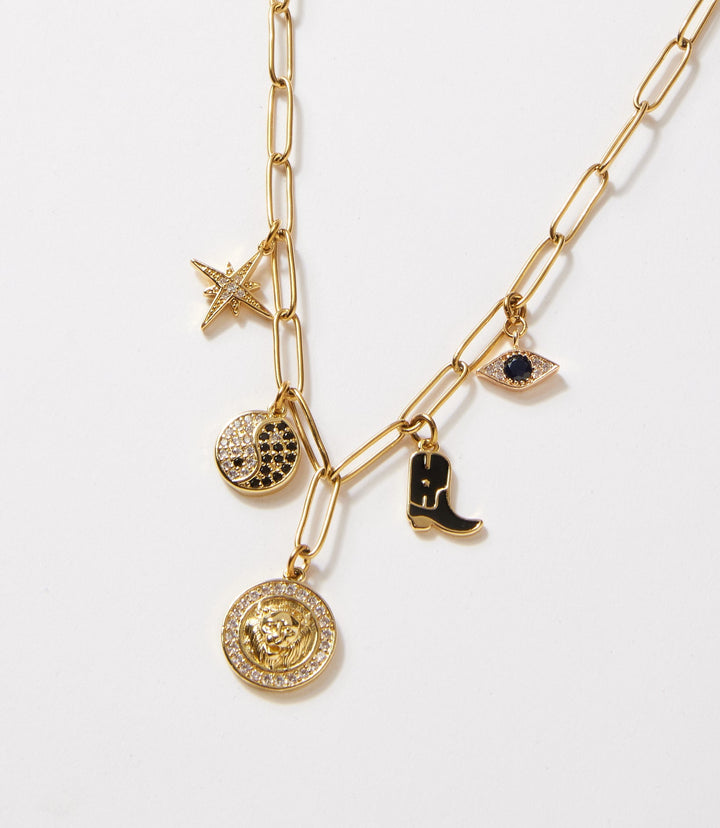 Charm Station Necklace with five gold charms including star, yin-yang, medallion, eye, and boot on a delicate gold chain