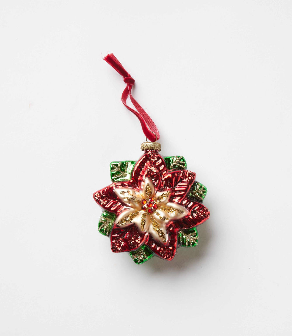 Red and gold glass flower ornament shaped like a poinsettia with green leaves and a red hanging ribbon