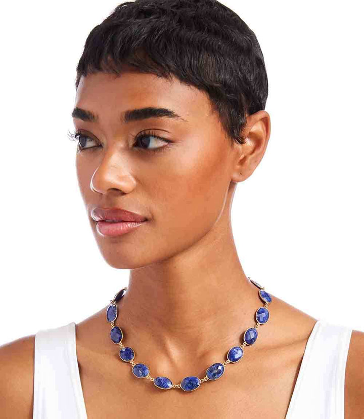 Woman wearing sapphire gemstone bezel necklace with blue stones and gold detailing