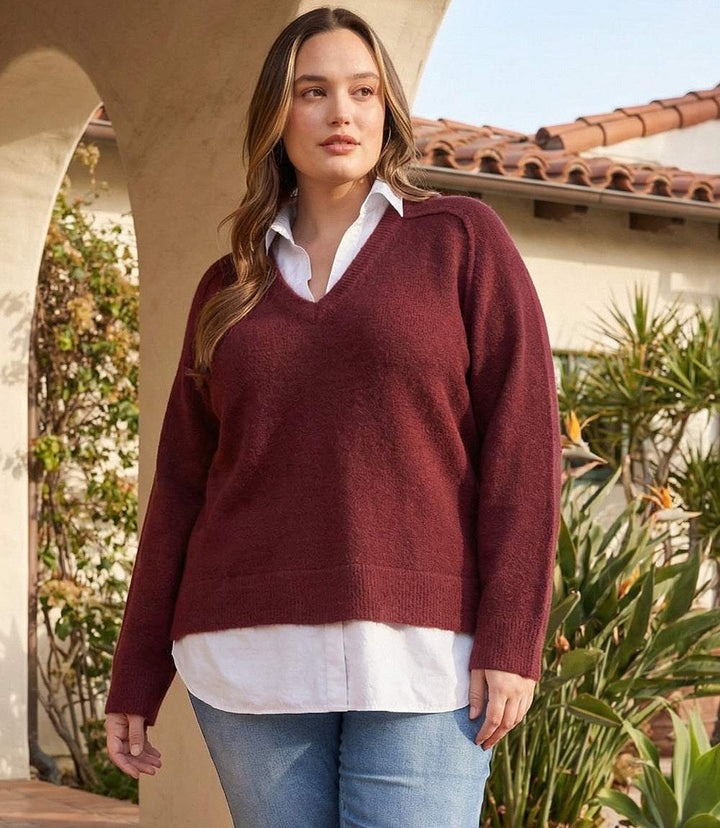 Plus size layered sweater with V-neck, shirt collar, raglan sleeves, and faux-layered hem detail