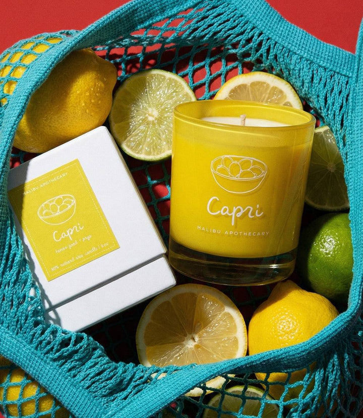 Capri Candle in yellow glass with citrus and floral scent, soy wax, and eco-friendly ingredients