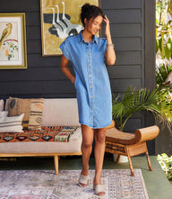 Woman wearing cap sleeve denim shirtdress with snap front and shirttail hem