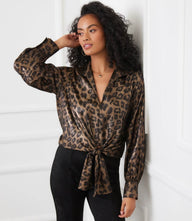 Woman wearing shimmer leopard print long sleeve tie-front top with plunging neckline and buttoned cuffs