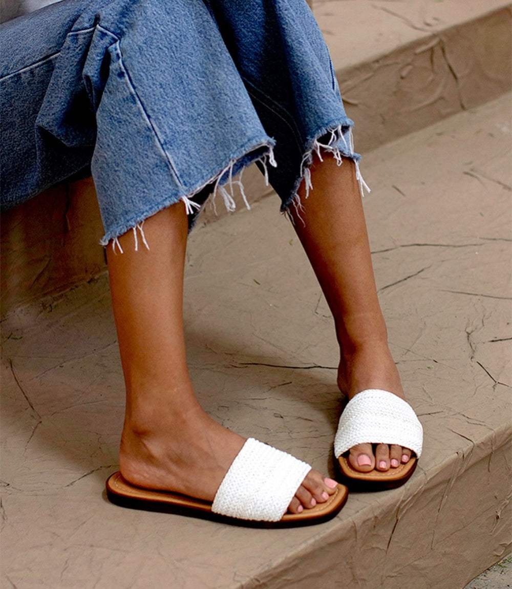 Palm Perfection Sandals white synthetic raffia square toe slides on feet with denim jeans on steps