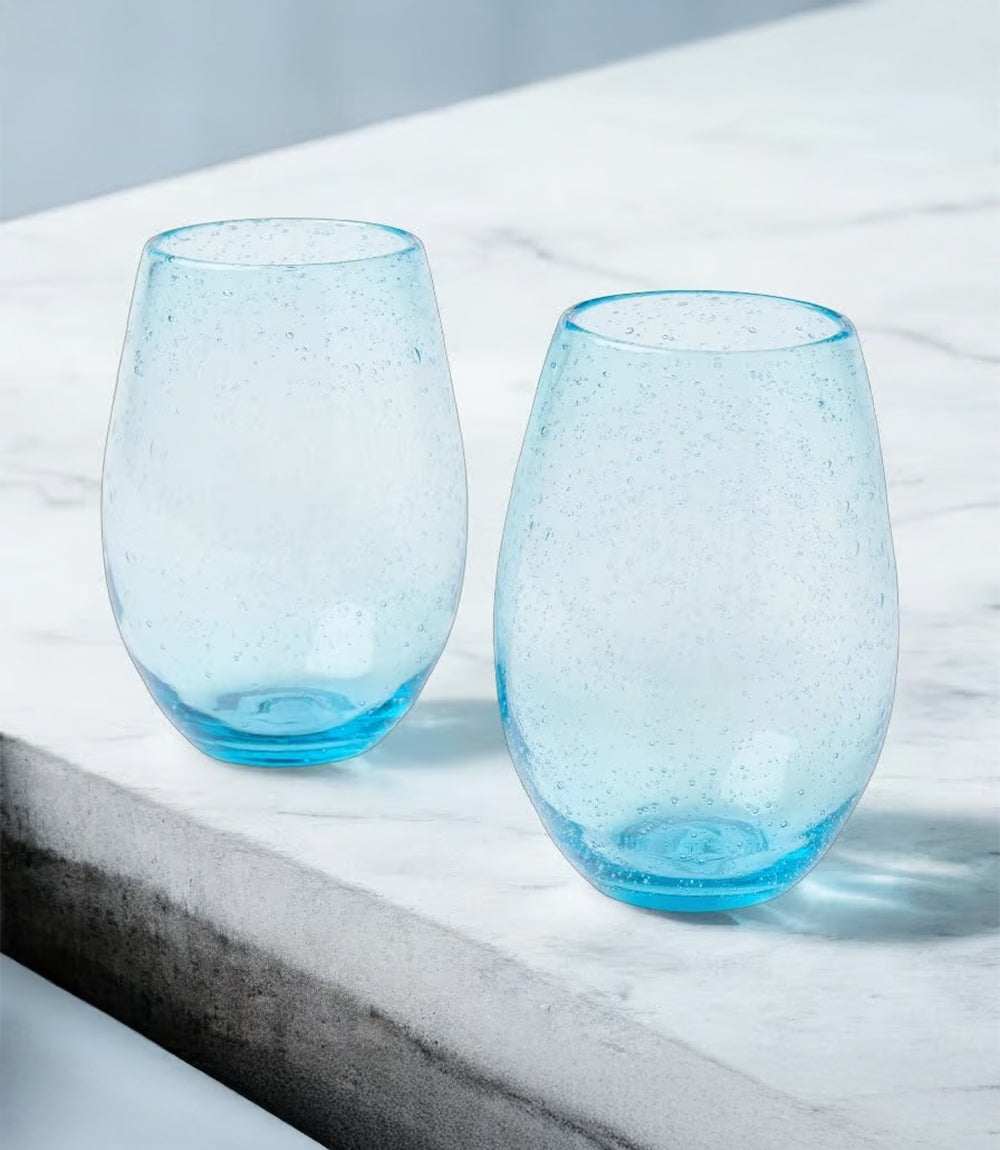 Two turquoise stemless bubble wine glasses on a marble surface