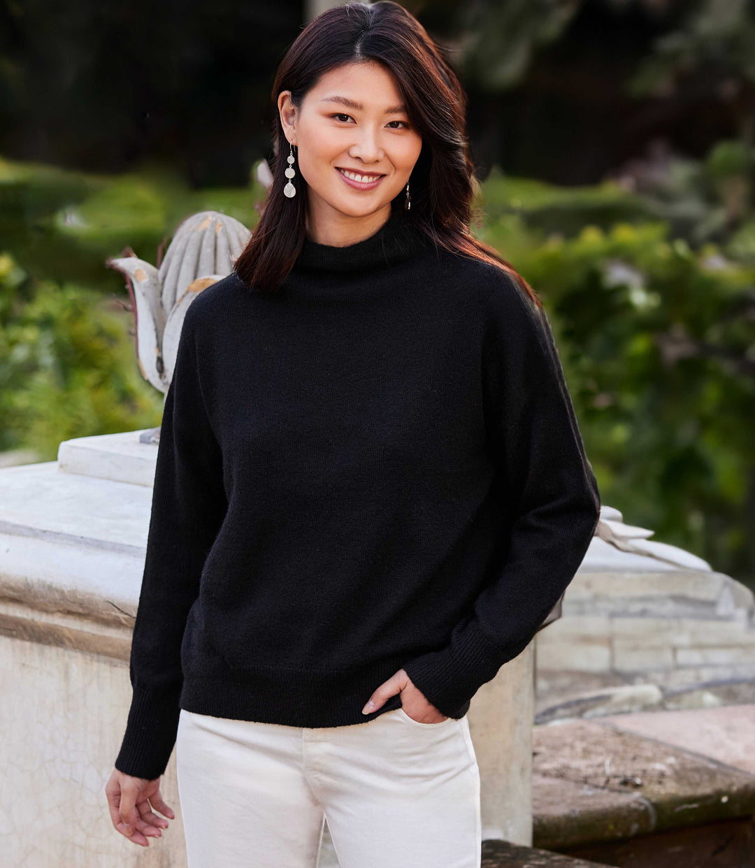 Woman wearing black mock neck sweater with ribbed cuffs and hem in outdoor setting