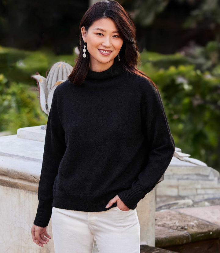 Woman wearing black mock neck sweater with ribbed cuffs and hem in outdoor setting