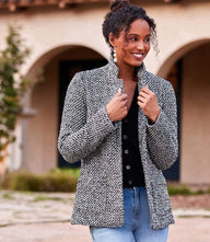 Woman wearing a textured woven tweed blazer with collar and front pockets, styled over a black top and jeans outdoors