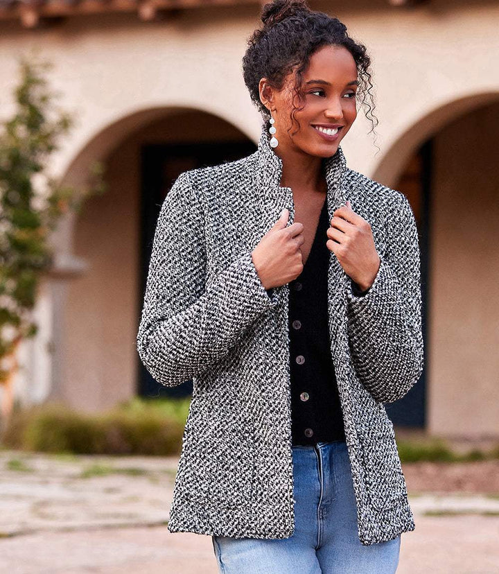 Woman wearing a textured woven tweed blazer with collar and front pockets, styled over a black top and jeans outdoors