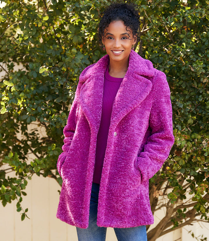 Woman wearing a vibrant purple sherpa coat with wide collar and side pockets outdoors