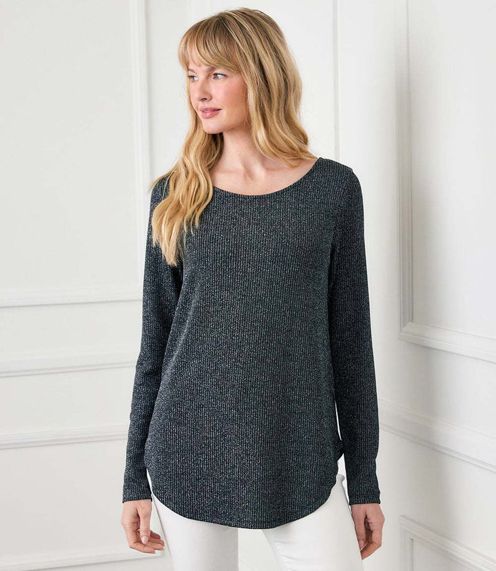 Woman wearing a long sleeve metallic stripe knit top with scoop neck and shirttail hem
