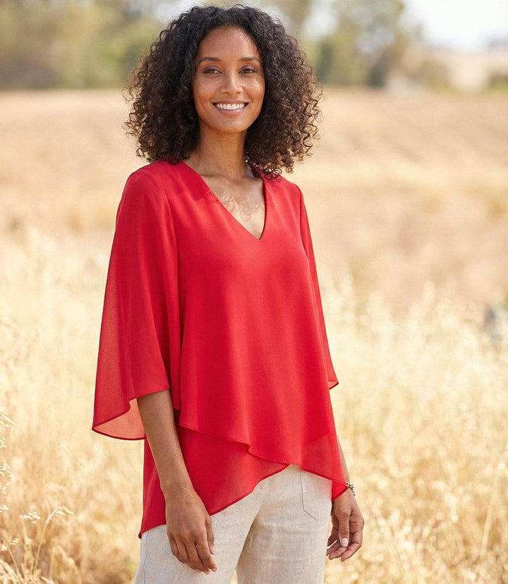 Woman wearing a silky crepe Bracelet Sleeve Asymmetric Top with flare sleeves and layered hem