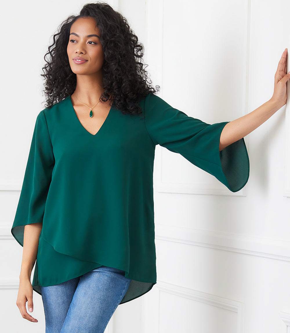 Woman wearing petite size green bracelet sleeve asymmetric top with V-neck and layered hem