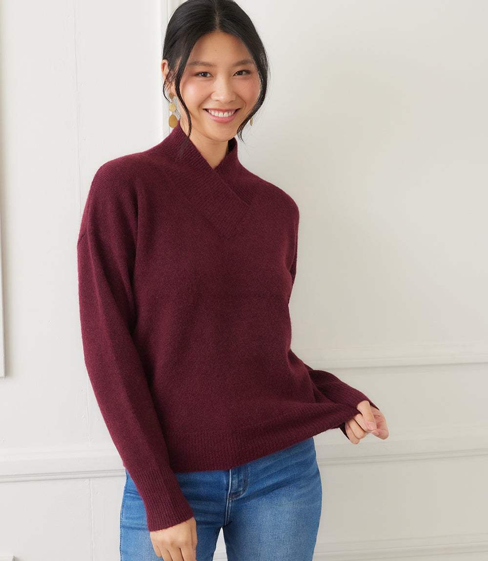 Woman wearing burgundy shawl collar sweater with drop shoulders and ribbed cuffs, styled with blue jeans