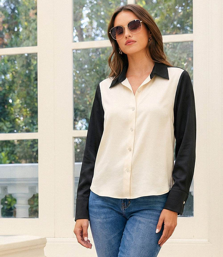Woman wearing long sleeve satin colorblock shirt with black sleeves and collar, button-down front, and relaxed fit