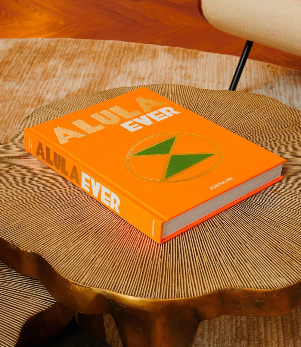 Alula Ever travel book with bright orange cover on wooden table