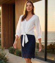 Woman wearing a white blouson sleeve top with tie-front detail and V-neckline