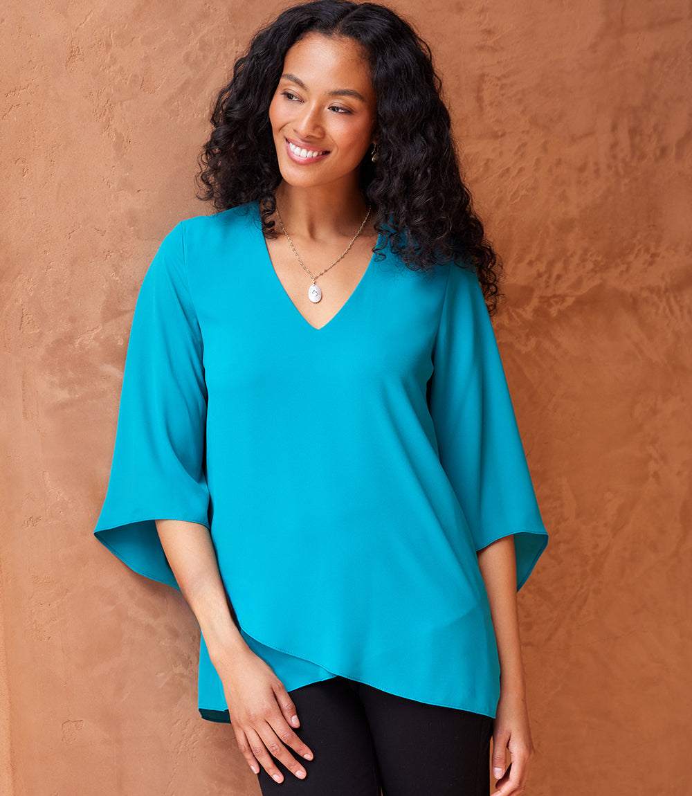 Woman wearing a turquoise bracelet sleeve asymmetric top with V-neck and layered hem
