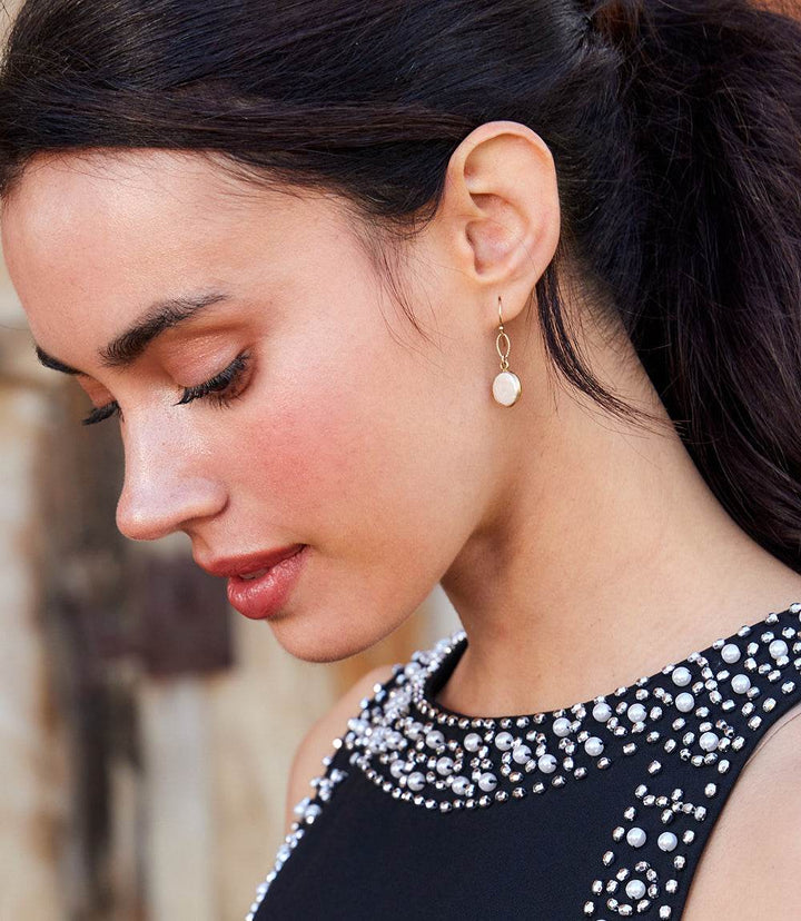 Close-up of woman wearing elegant gold filled pearl earrings with semi-precious gemstones