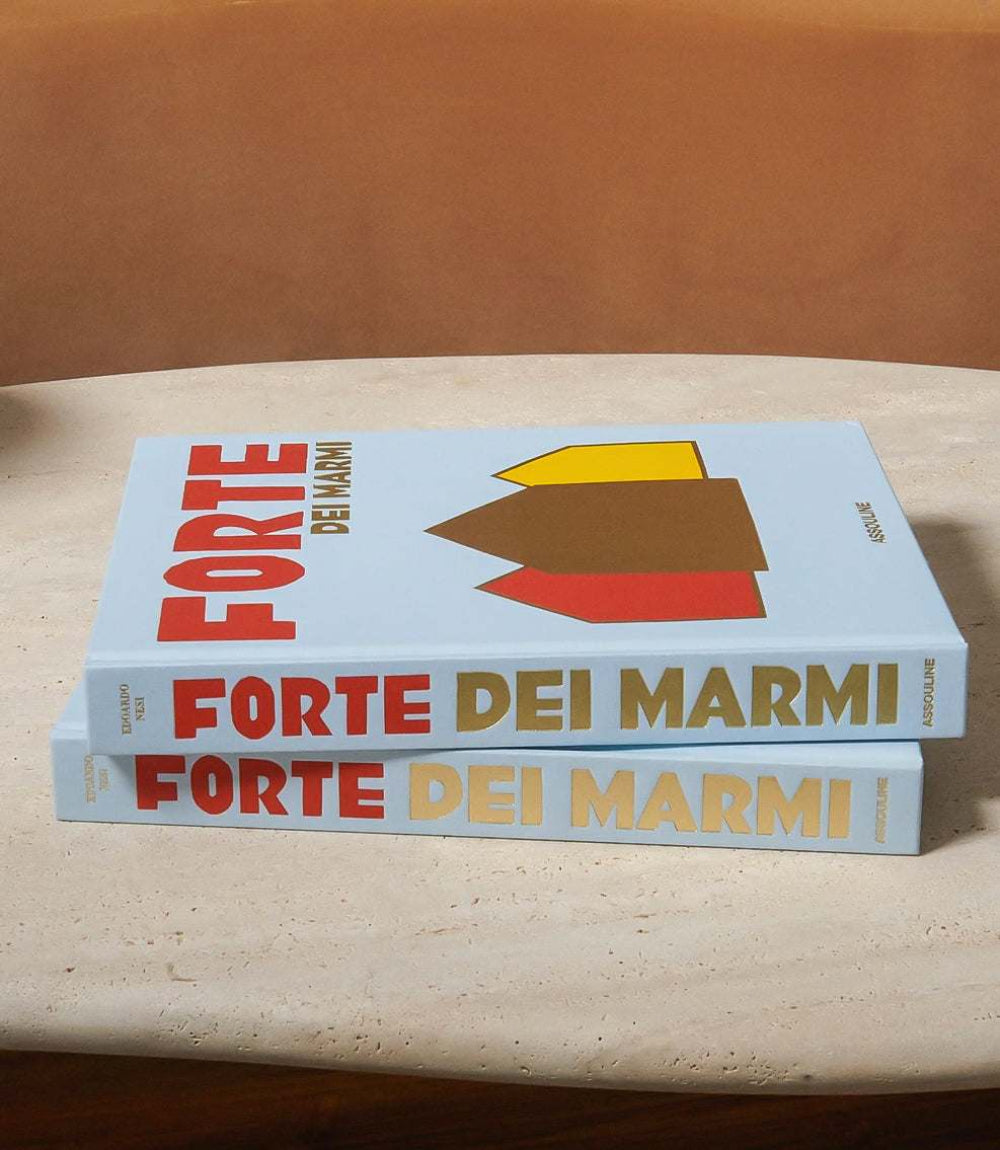 Stack of two hardcover books titled Forte Dei Marmi with colorful geometric shapes on cover, placed on a stone table