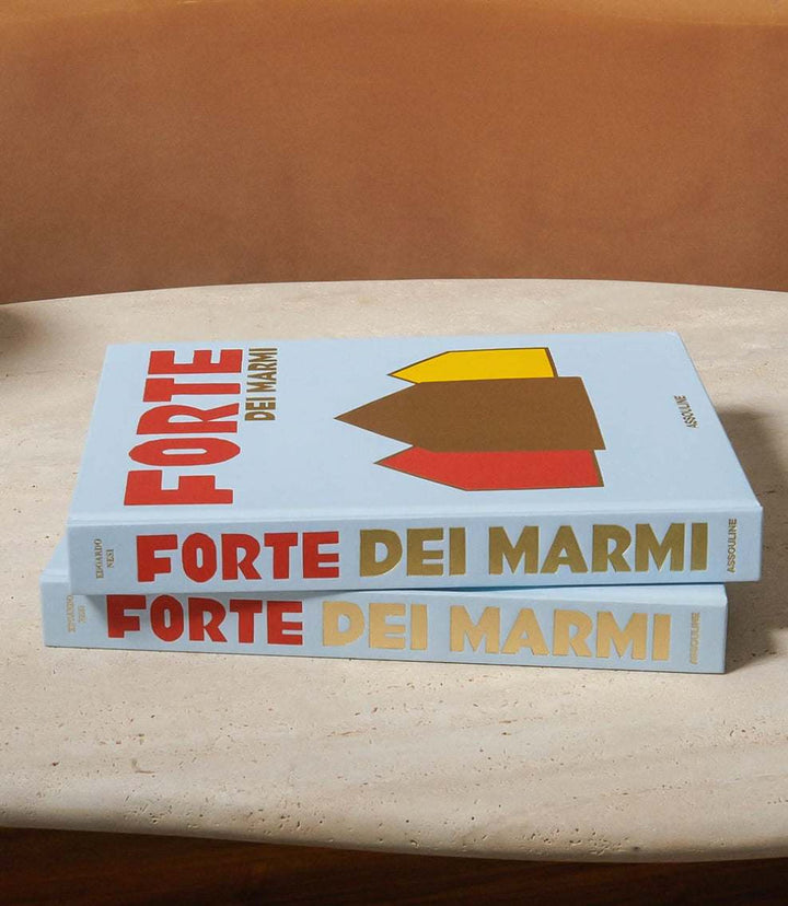 Stack of two hardcover books titled Forte Dei Marmi with colorful geometric shapes on cover, placed on a stone table